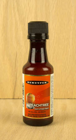 RIVER FALLS,WISCONSIN-JULY 14,2017: A bottle of Dekuyper brand peach flavored schnapps with a wood background.のeditorial素材