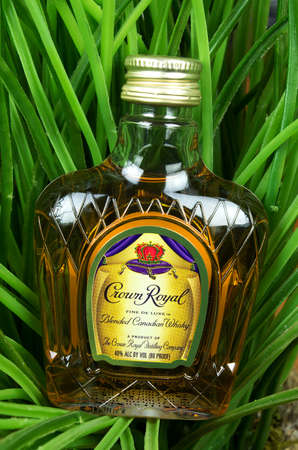 RIVER FALLS,WISCONSIN-AUGUST 10,2017: A bottle of Crown Royal brand whiskey against a greenery background.のeditorial素材