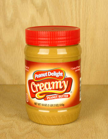 RIVER FALLS,WISCONSIN-SEPTEMBER 09,2017: A jar of Peanut Delight brand creamy peanut butter with a wood background.のeditorial素材