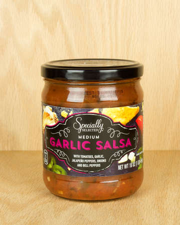 RIVER FALLS,WISCONSIN-SEPTEMBER 11,2017: A jar of garlic flavored salsa with a wood background.のeditorial素材