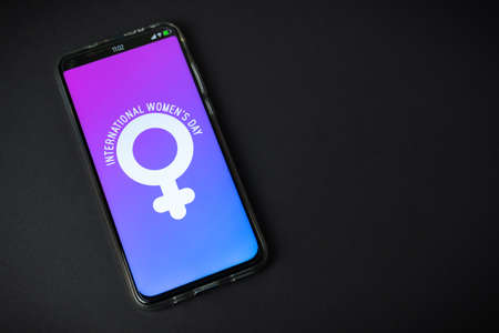 Phone with International Women's Day symbol on black backgroundの写真素材