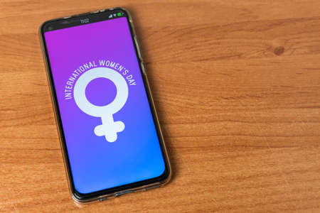 Phone with International Women's Day symbol on tableの写真素材