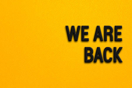We are back - words on yellow backgroundの写真素材