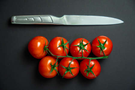 Cherry tomatoes and knife on black backgroundの写真素材