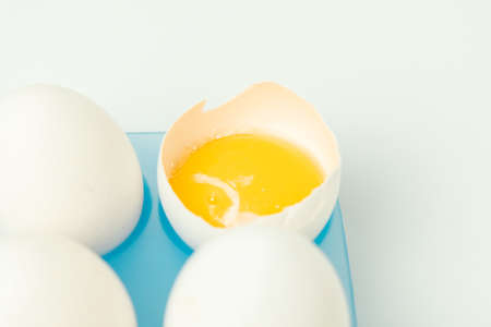 Chicken eggs and one broken egg with yolkの写真素材