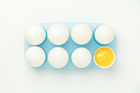 Chicken eggs and one broken egg with yolkの写真素材