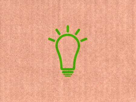 Green light bulb icon on cardboard textureの写真素材