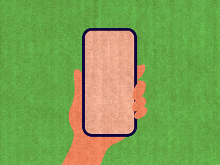 Hand holding a phone on a green cardboard textureの写真素材