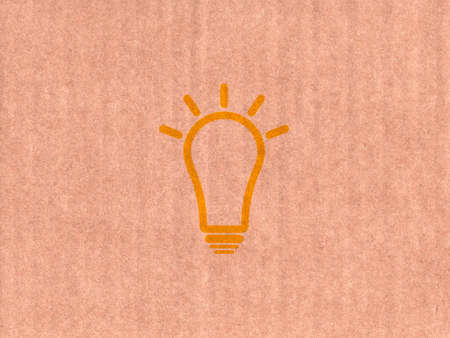 Yellow light bulb icon on cardboard textureの写真素材