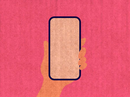 Hand holding a phone on a pink cardboard textureの写真素材