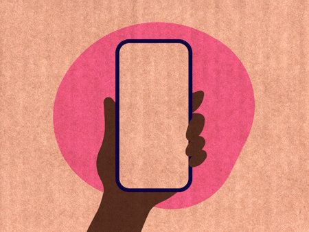 Hand holding a phone on a pink cardboard textureの写真素材