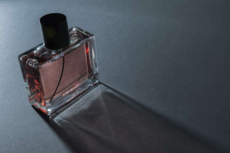 A bottle of perfume on black background in the rays of lightの写真素材
