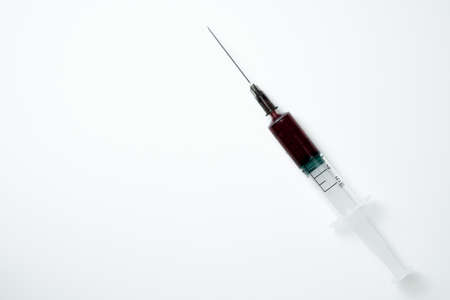 Medical syringe and needle with red blood on a light backgroundの写真素材