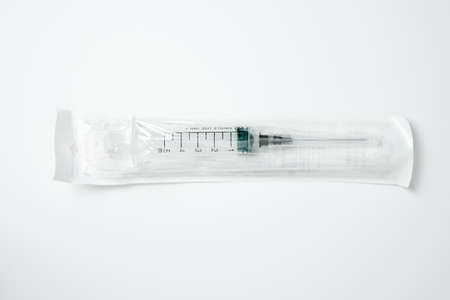 Medical syringe and needle in a package on a light backgroundの写真素材