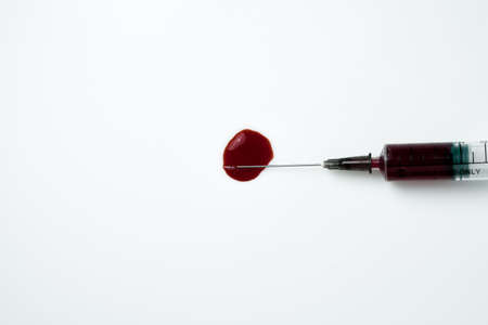 Medical syringe and needle with a drop of blood on a light backgroundの写真素材