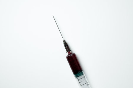 Medical syringe and needle with red blood on a light backgroundの写真素材