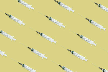 Seamless pattern with medical syringe and needle on yellow backgroundの写真素材