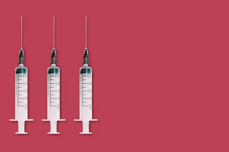 Medical syringe and needle on red background with space for textの写真素材