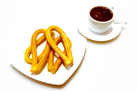 Churros and chocolate traditional spanish breakfast on a plate on white backgroundの写真素材