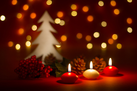 Christmas candles and ornaments over red dark background with lightsの写真素材
