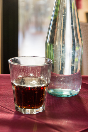 A beautifully backlit glass of red soft drink on a restaurant table in Italy at sunsetの写真素材
