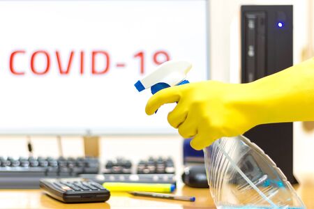 Disinfecting of an office with spray and glove to prevent COVID-19 diseaseの写真素材