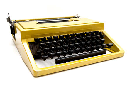 Studio photo of a vintage mustard yellow typewriter on a white backgroundの写真素材