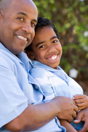 Portrait of an African American father and son outside at the park.