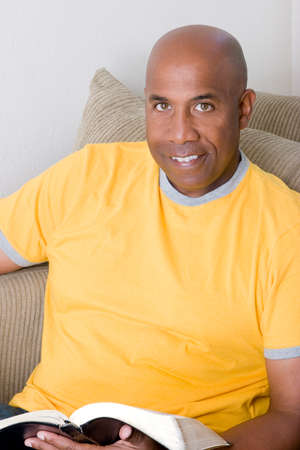 African American man sitting on a sofa and reading.の写真素材