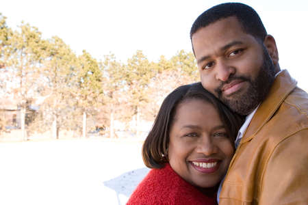 African American couple laughing and hugging in front of their home.の写真素材