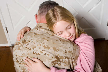 Happy young girl hugging her father in uniformの写真素材