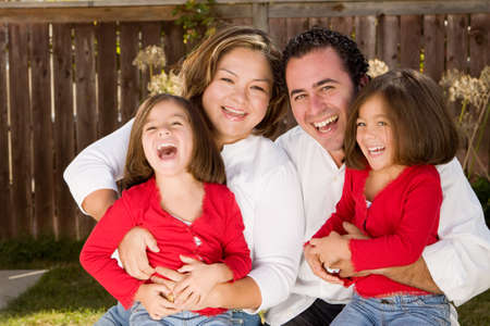 Happy Hispanic mother and father with their daughters.の写真素材