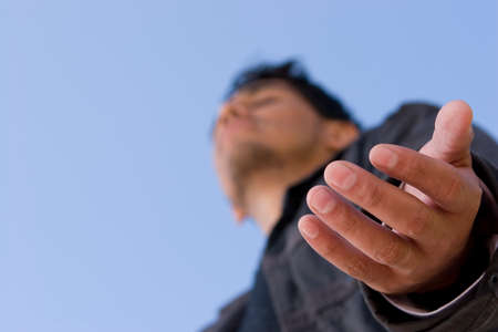 Hispanic man with open arm in prayer.の写真素材