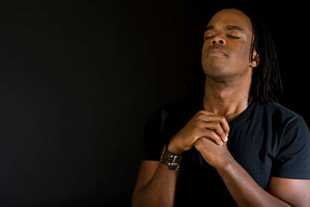 Man in deep thought praying isolated on black.