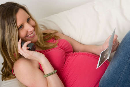 Pregnant woman looking at an ultrasound photo of her babyの写真素材
