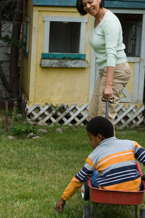 Little boy in wagon being pulled by his mom.