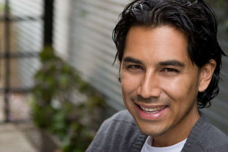 Happy Hispanic man smiling and standing outside.の写真素材