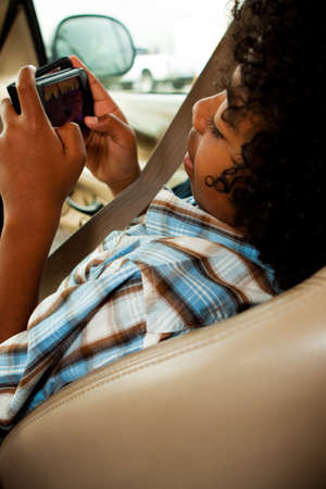 African American kid sitting in the front seat playing a game