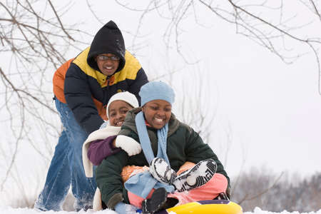 African American brothers and sister sliding on a sled.の写真素材