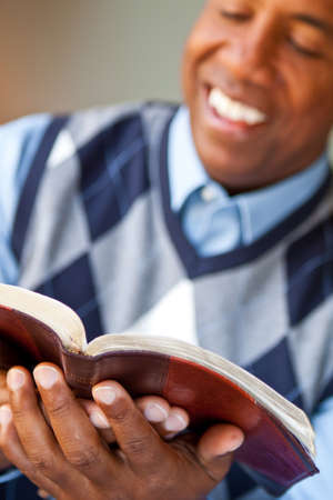 African American man sitting on a sofa reading.
