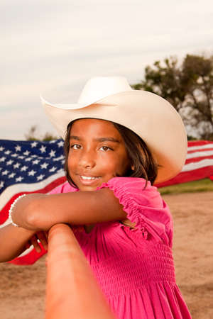 Hispanic little girl wearing a hat with an American flag.の写真素材