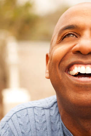 Mature African American man smiling sitting outside.