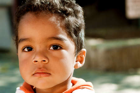 Little boy sitting outside looking at the camera.