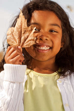 Happy little girl playing with a leaf.
