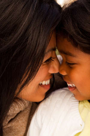 Biracial mother and daughter laughing and smiling outside.の写真素材