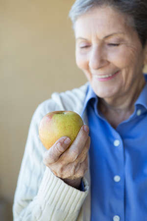 Elderly woman eating an apple.の写真素材