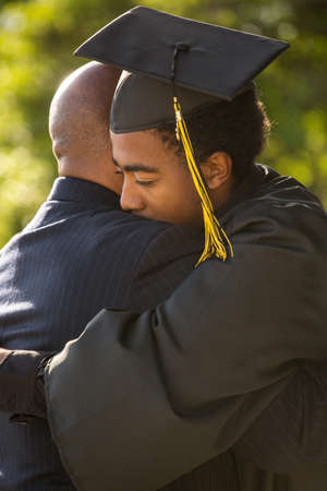 Father hugging his son at his graduation.の写真素材
