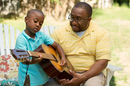 Father teaaching his his son to play the guitar.の写真素材