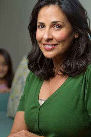 Beautiful Confident Hispanic Woman Smiling with a child in the background.の写真素材