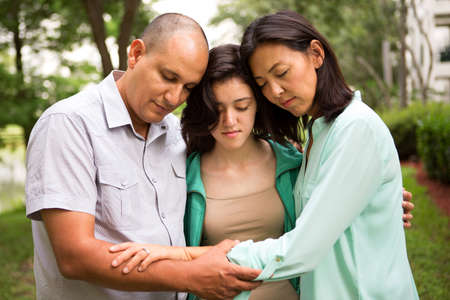 Portrait of a family praying with their daughter.の写真素材